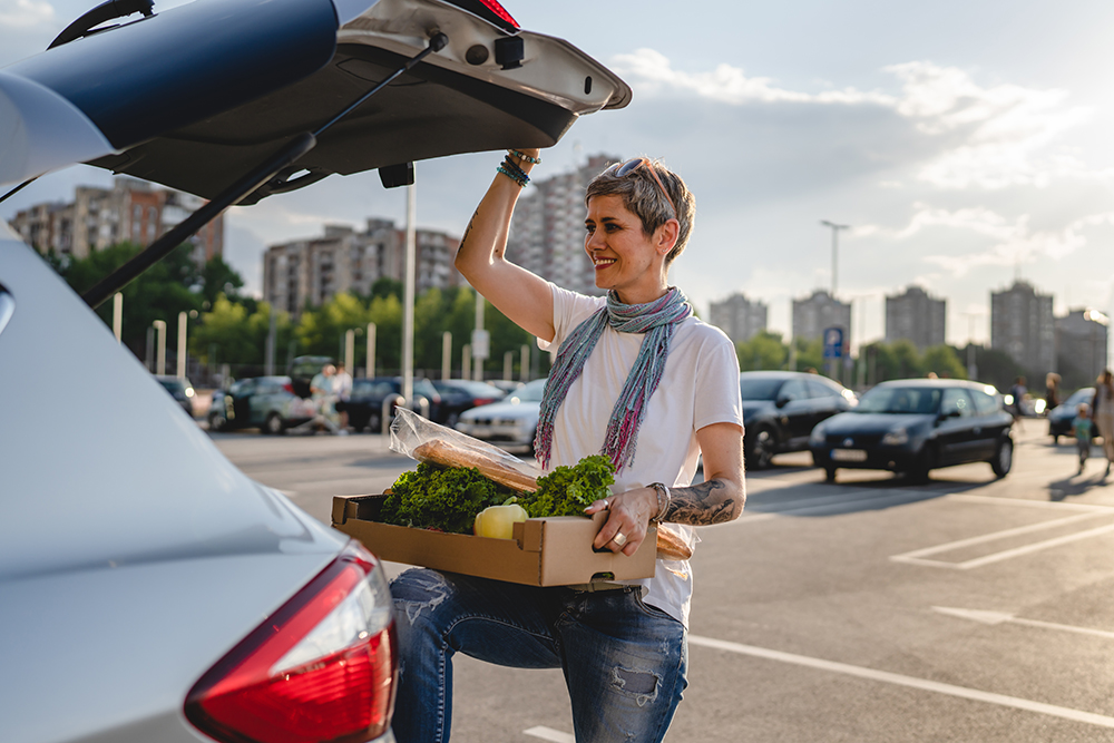 Woman placing vegetables into her trunk